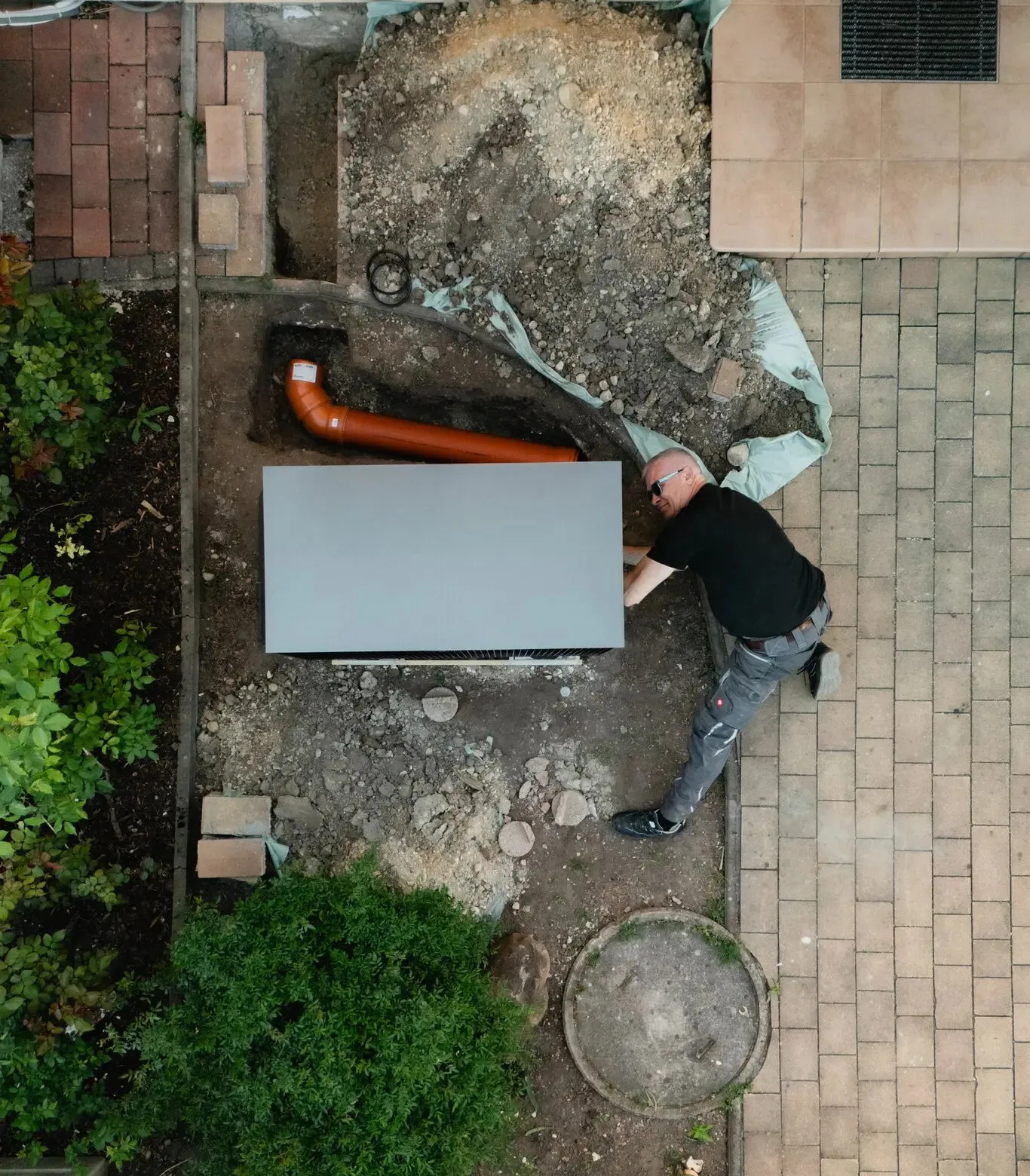 Heizma-Techniker an einer Viessmann-Wärmepumpe im Garten, aus der Vogelperspektive
