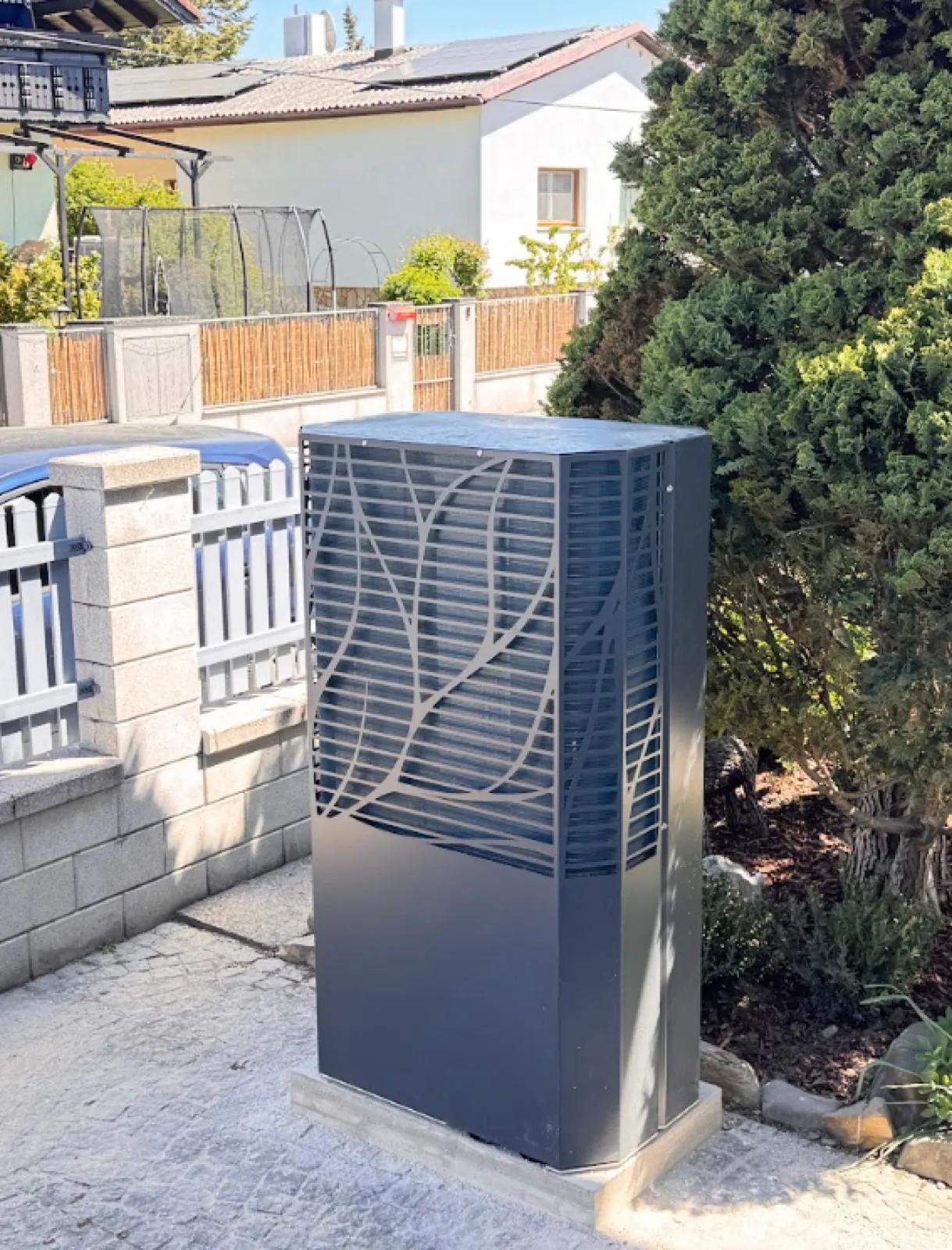 Wärmepumpe mit Design-Verkleidung, eingefügt in den Vorgarten.
