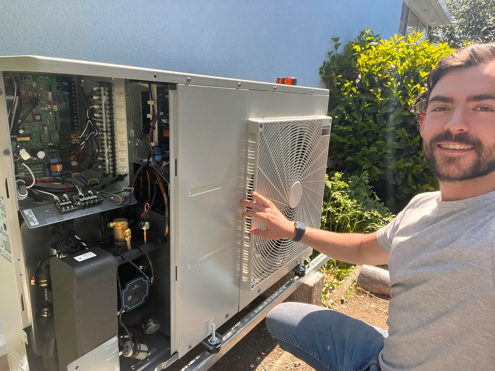 Heizma-Techniker macht ein Selfie neben einer geöffneten Wärmepumpe
