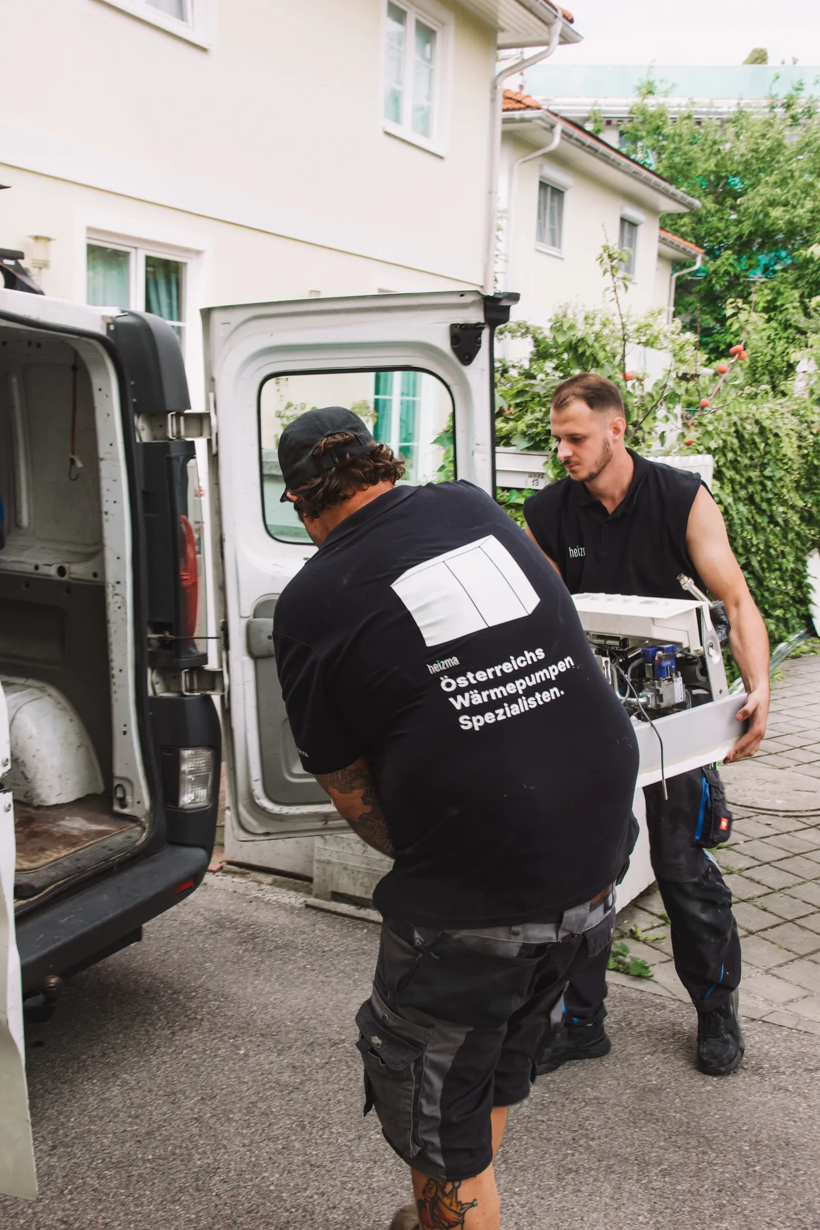 Zwei Heizma-Techniker liefern eine Wärmepumpe beim Kundenhaus an